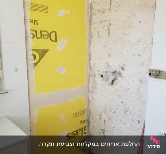 קיר עם לוח גבס צהוב ותשתית טיח חשופה